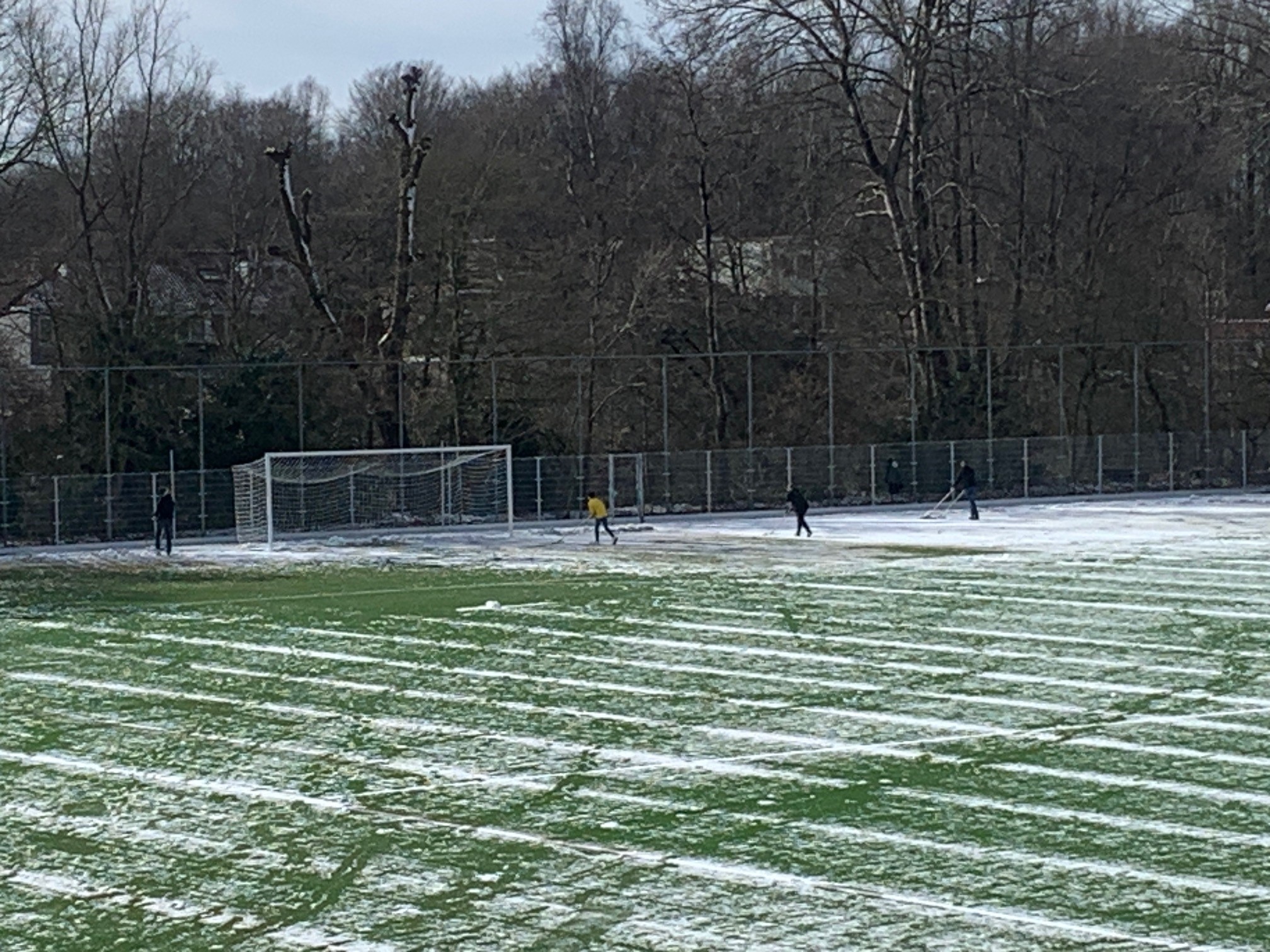 Vrijwilligers schuiven de velden sneeuwvrij voor het namiddagprogramma.
